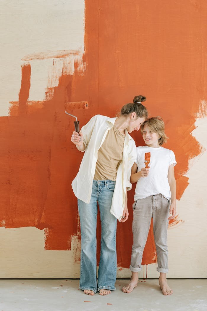 services-03 Mother and son smiling while painting a wall together in a home renovation project.